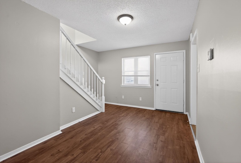 Entryway with stairs, a textured ceiling, and dark wood finished floors