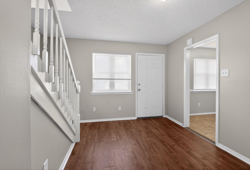 Foyer entrance featuring stairway, dark wood-style flooring, a textured ceiling, and plenty of natural light