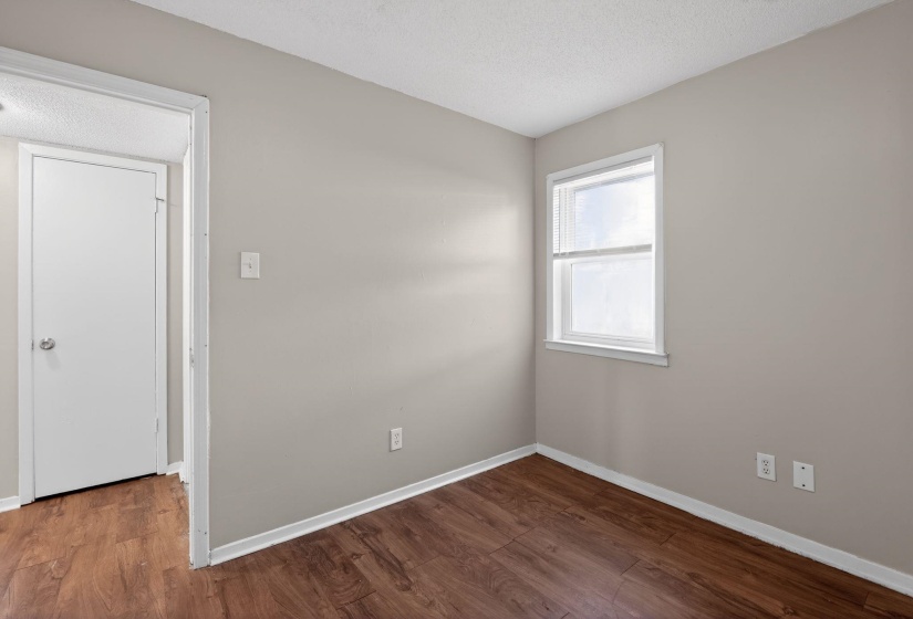 Empty room featuring dark wood-type flooring and a textured ceiling