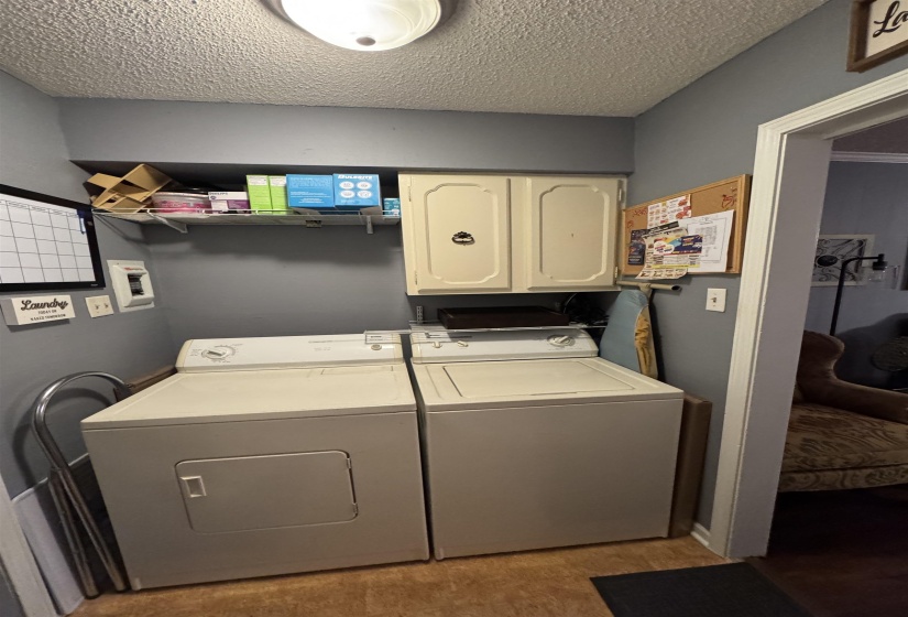 Laundry area with washer and clothes dryer, cabinet space, and a textured ceiling