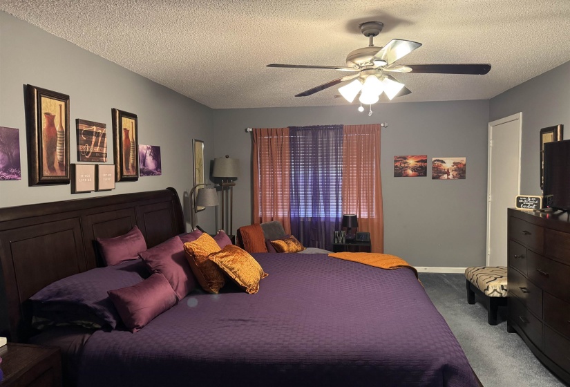 Carpeted bedroom featuring ceiling fan and a textured ceiling