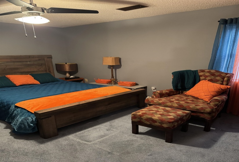 Bedroom featuring carpet, a ceiling fan, and a textured ceiling
