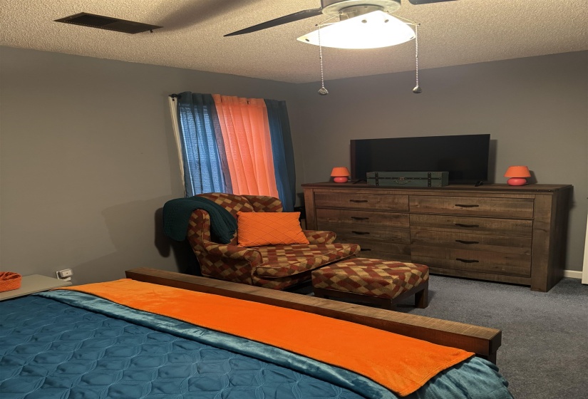 Bedroom with a ceiling fan, a textured ceiling, and carpet floors