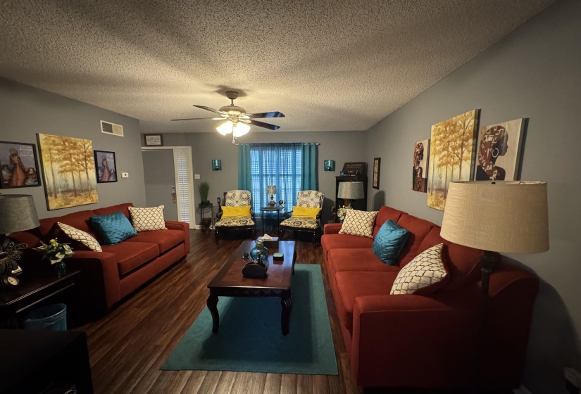 Living area featuring wood finished floors, a textured ceiling, and ceiling fan