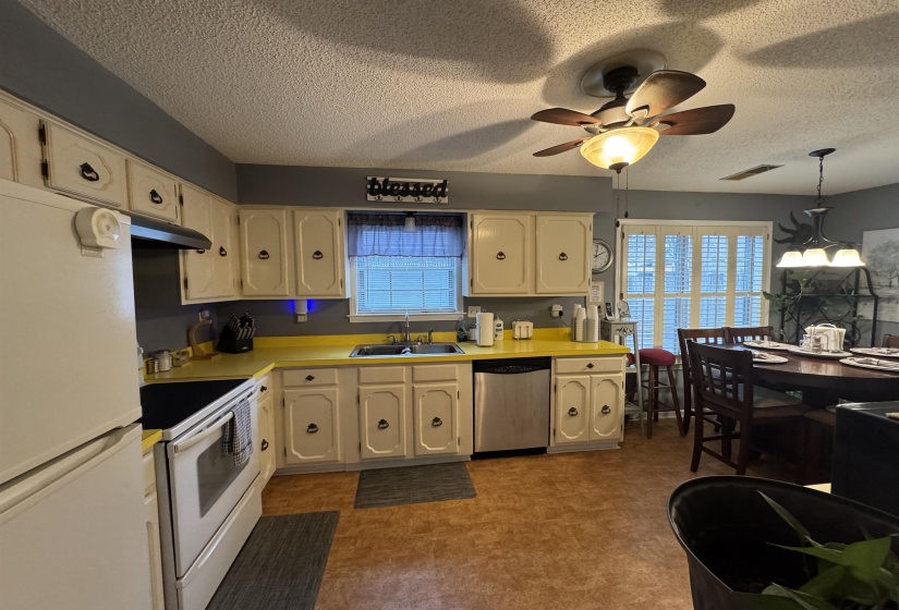 Kitchen with white appliances, light countertops, dark floors, a textured ceiling, and a ceiling fan