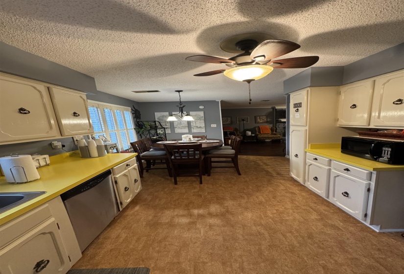 Kitchen with light countertops, decorative light fixtures, black microwave, dishwasher, and a textured ceiling