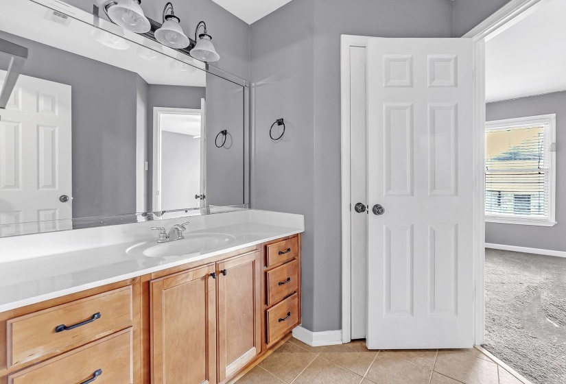 Bathroom with vanity, light tile patterned floors, and light colored carpet