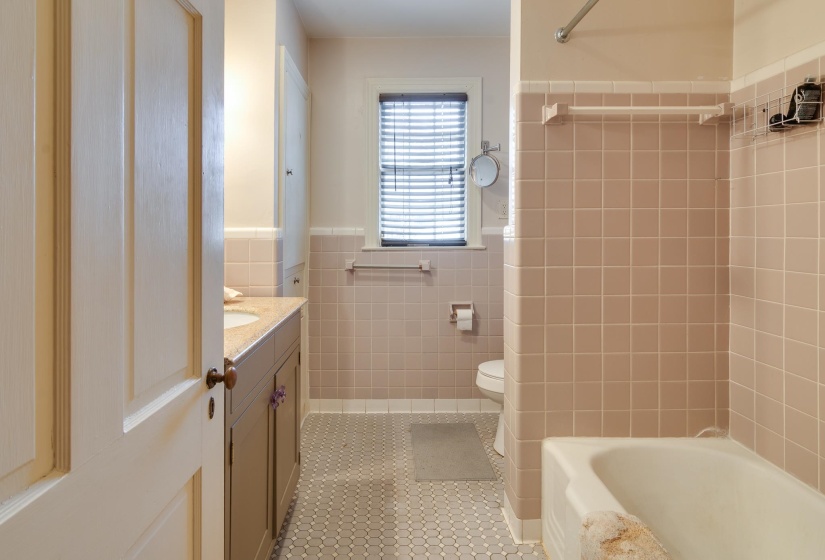 Bathroom featuring vanity, a wainscoted wall, tile walls, bathing tub / shower combination, and light tile patterned floors
