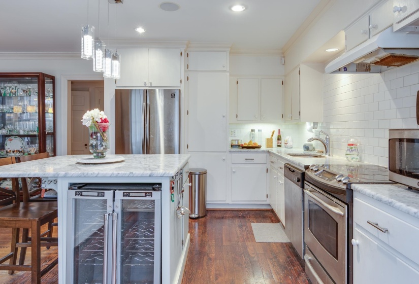 Kitchen featuring ornamental molding, stainless steel appliances, wine cooler, a kitchen breakfast bar, and under cabinet range hood