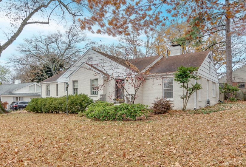 View of property exterior featuring brick siding, a chimney, and a yard
