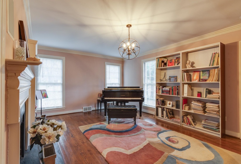 Living area with ornamental molding, a fireplace, dark wood-type flooring, and a chandelier