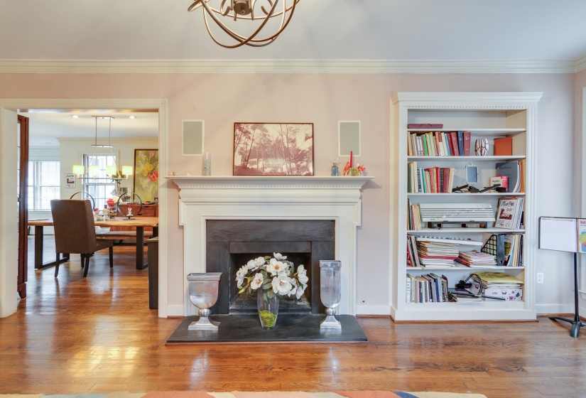 Living room with a chandelier, a fireplace with raised hearth, wood finished floors, and ornamental molding