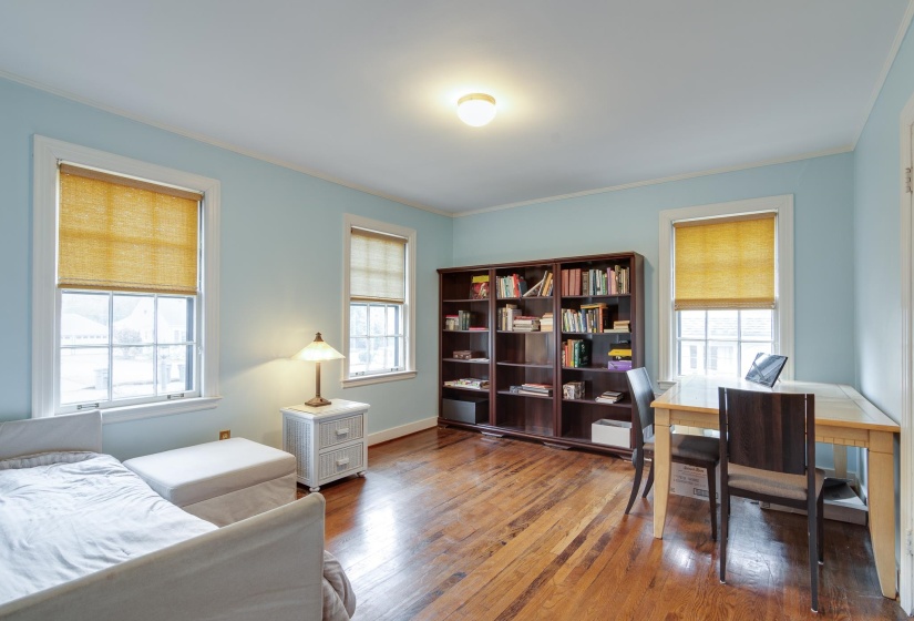 Bedroom featuring multiple windows, hardwood / wood-style floors, an office area, and crown molding