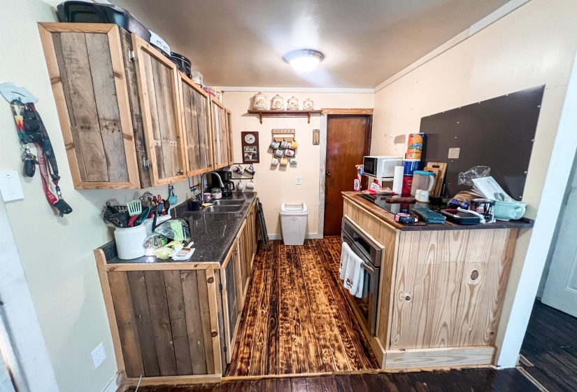 Kitchen featuring dark countertops, oven, and dark wood finished floors.