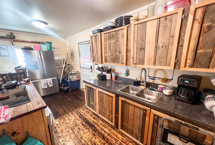 Kitchen featuring stainless steel fridge, dark countertops, and dark wood-type flooring.