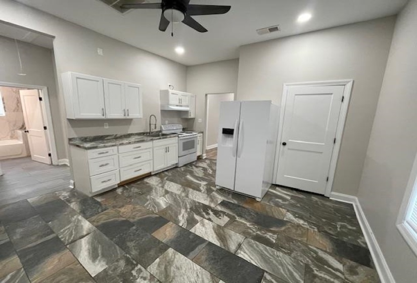 Kitchen with white appliances, white cabinets, ceiling fan, dark countertops, and recessed lighting