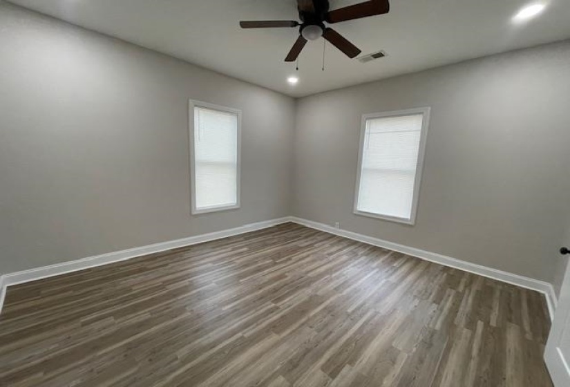 Empty room with dark wood-type flooring, recessed lighting, healthy amount of natural light, and ceiling fan