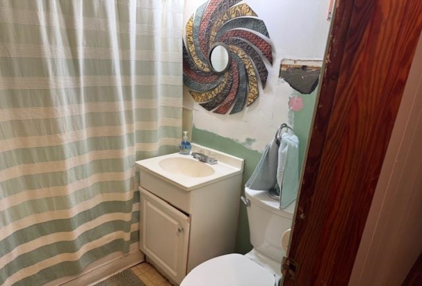 Full bath featuring a shower with shower curtain, vanity, and light tile patterned flooring