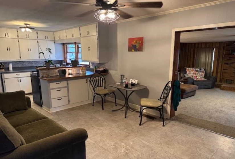 Kitchen with open floor plan, dark countertops, a peninsula, ceiling fan, and crown molding