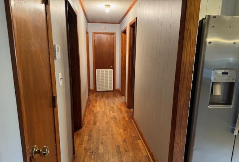 Hall featuring ornamental molding, light wood-type flooring, and wooden walls