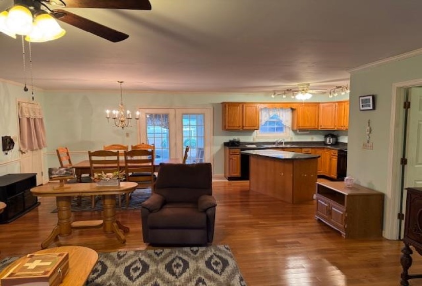 Living area with a ceiling fan, a chandelier, and dark wood finished floors
