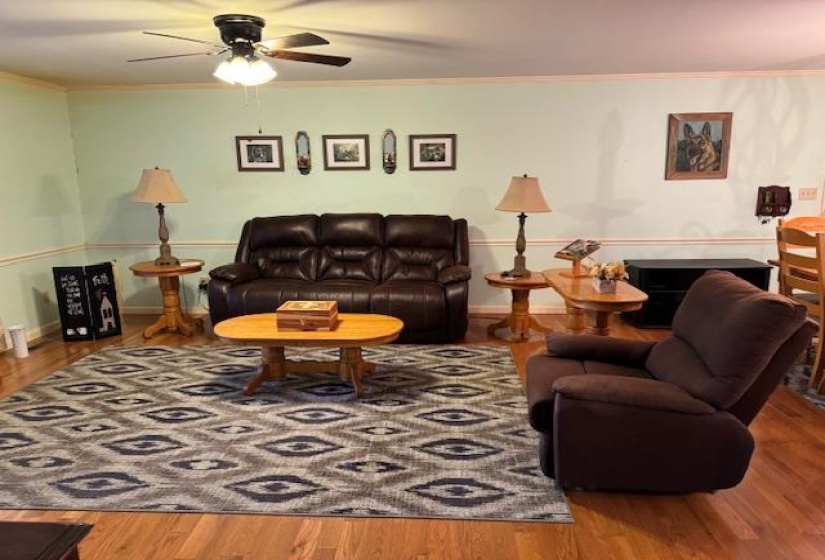 Living room featuring wood finished floors, ornamental molding, and ceiling fan