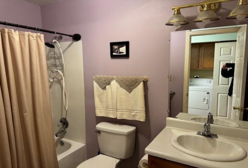 Bathroom featuring shower / tub combo with curtain, vanity, and washer / clothes dryer