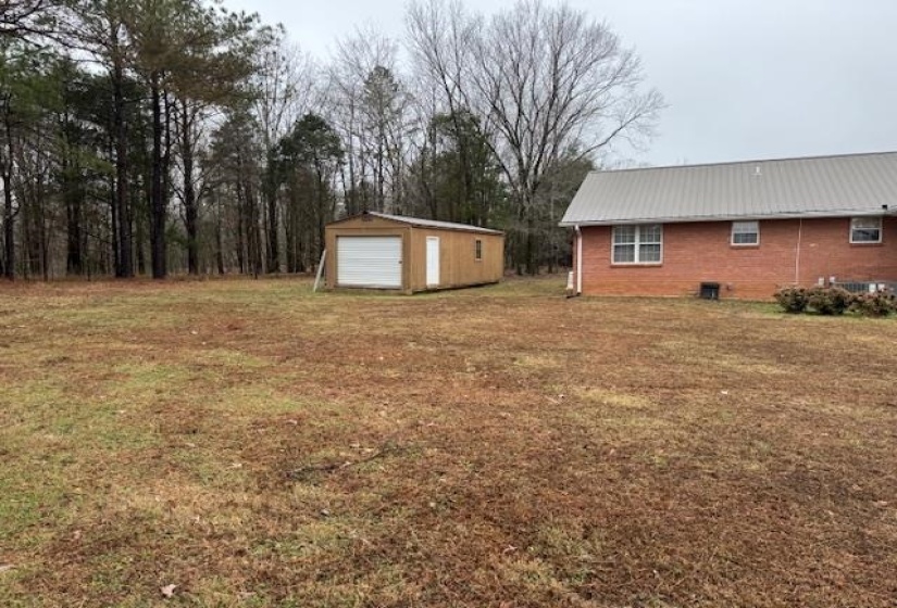 View of grassy yard featuring an outbuilding and a garage