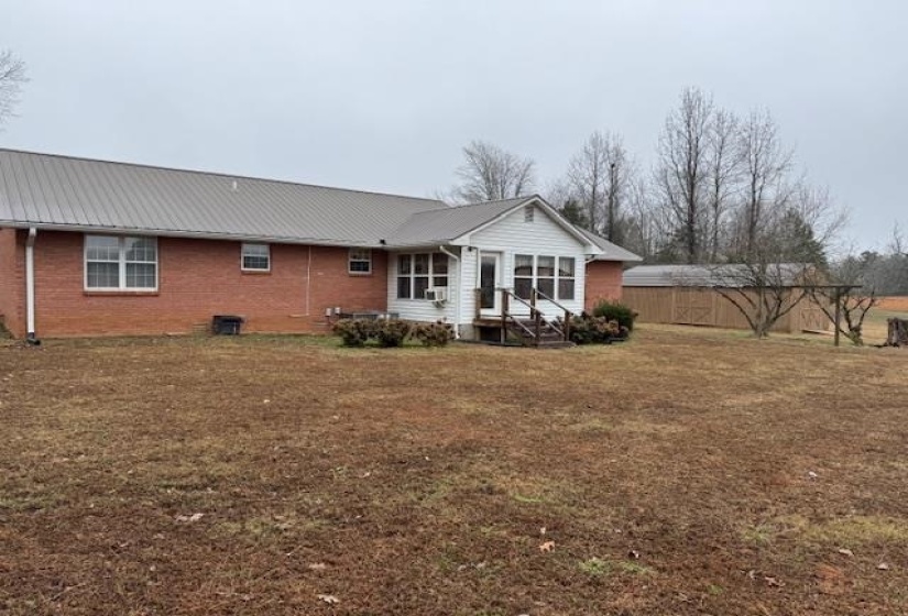 Back of house with a metal roof and brick siding