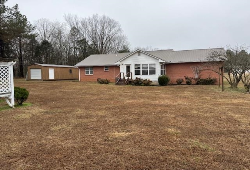 Back of house with an outbuilding and a yard