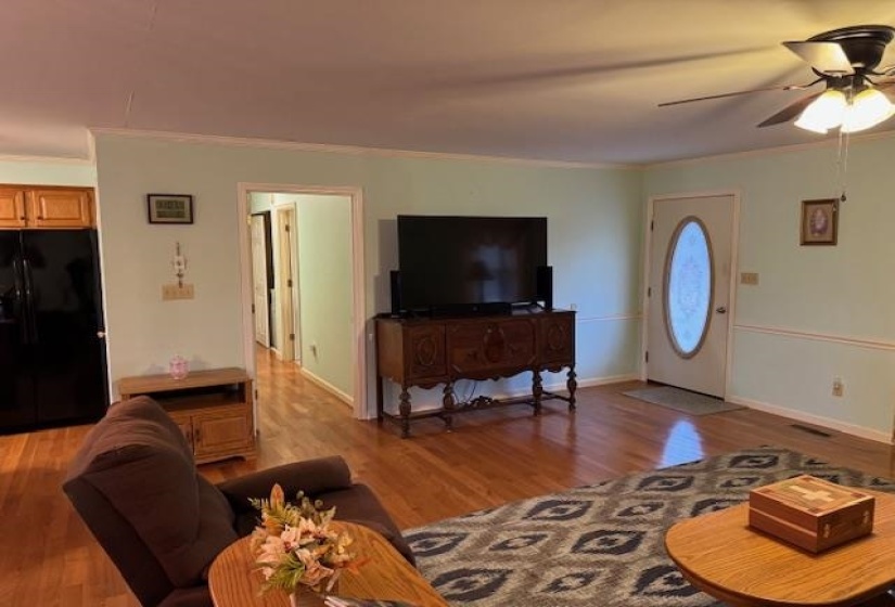 Living area with a ceiling fan, ornamental molding, and light wood-style floors