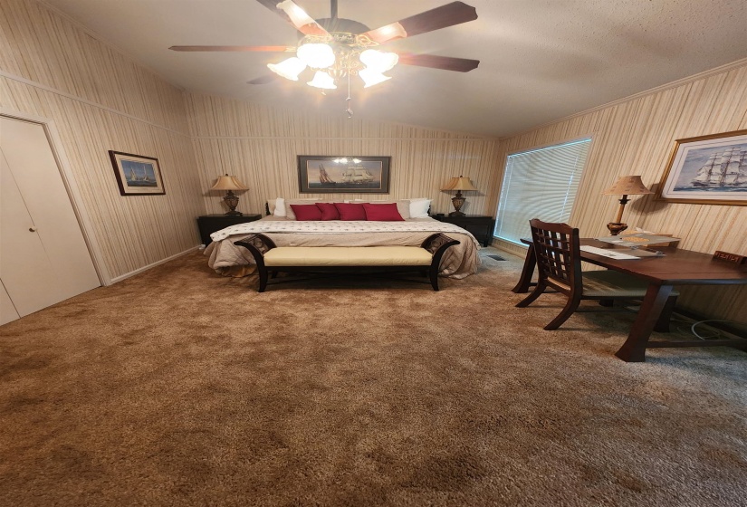Carpeted bedroom featuring a ceiling fan, vaulted ceiling, and a textured ceiling