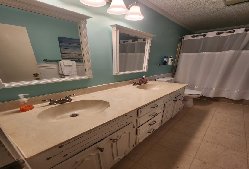 Bathroom with crown molding, light tile patterned floors, double vanity, a textured ceiling, and a shower with curtain