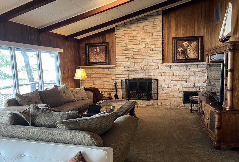 Living room with wood walls, a stone fireplace, and carpet flooring