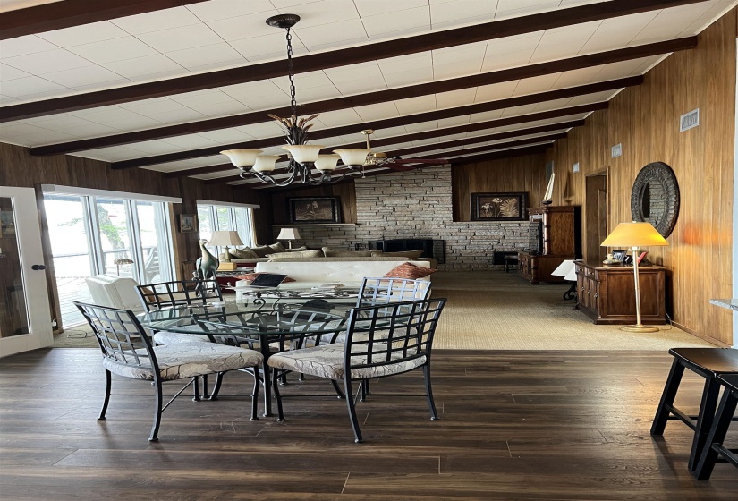 Dining room with wood walls, beamed ceiling, dark wood finished floors, and a chandelier