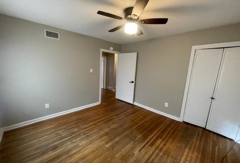 Unfurnished bedroom featuring dark wood-style flooring, ceiling fan, and a closet