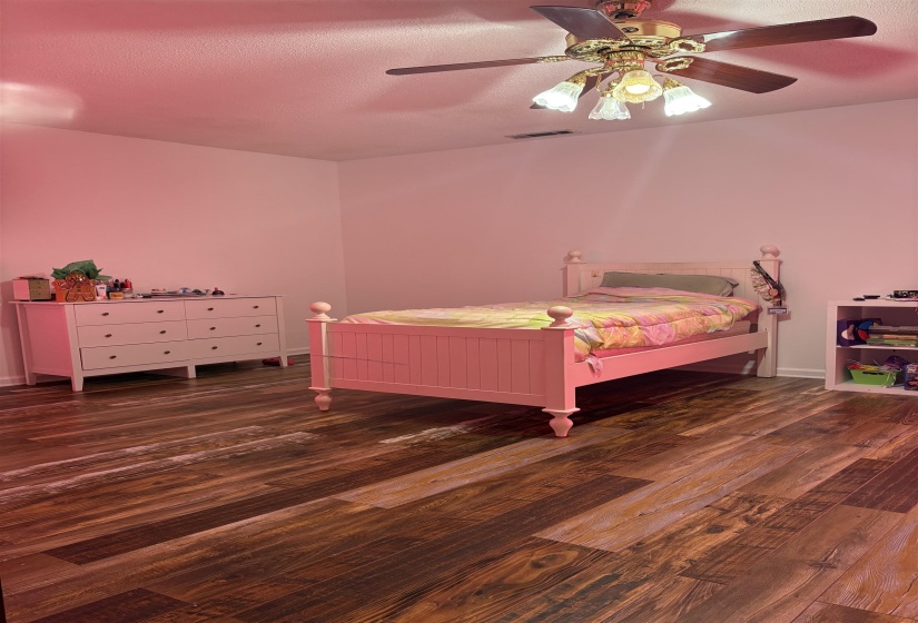 Bedroom with ceiling fan, dark wood finished floors, and a textured ceiling