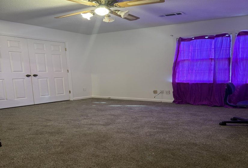 Unfurnished bedroom with dark colored carpet, a ceiling fan, and a closet