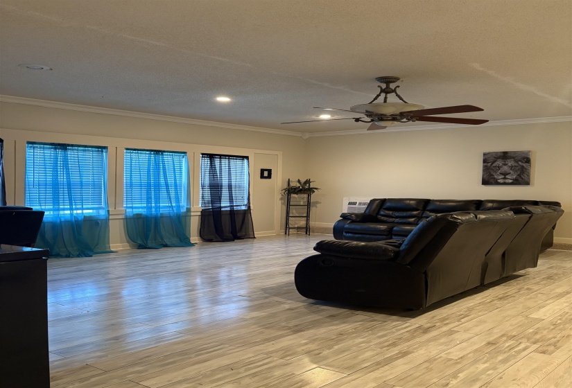 Living room with light wood-style floors, ceiling fan, ornamental molding, a textured ceiling, and recessed lighting