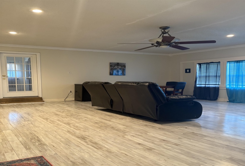 Living room with recessed lighting, plenty of natural light, crown molding, light wood-style floors, and a ceiling fan