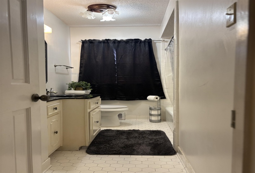 Full bath with vanity, a textured ceiling, shower / bath combo, and light tile patterned flooring