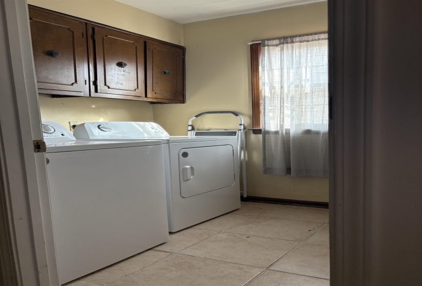 Washroom with cabinet space, independent washer and dryer, and light tile patterned floors