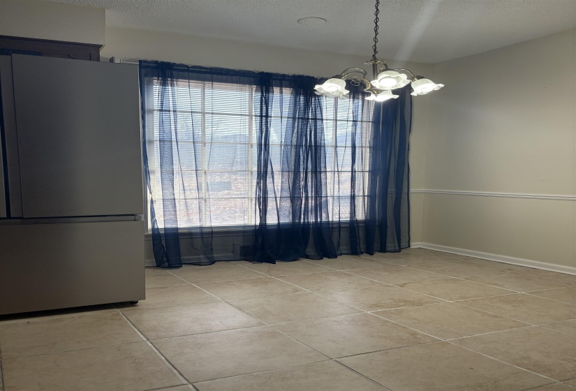Unfurnished dining area featuring a textured ceiling, a chandelier, and light tile patterned floors