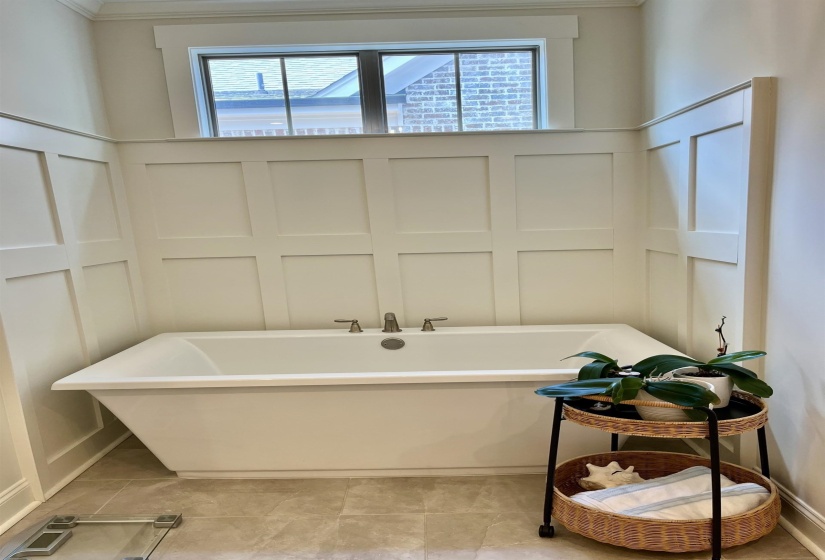 Bathroom with a decorative wall, a freestanding bath, ornamental molding, and tile patterned floors