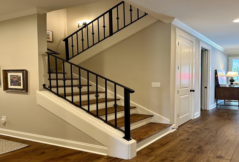 Stairway with crown molding and wood finished floors