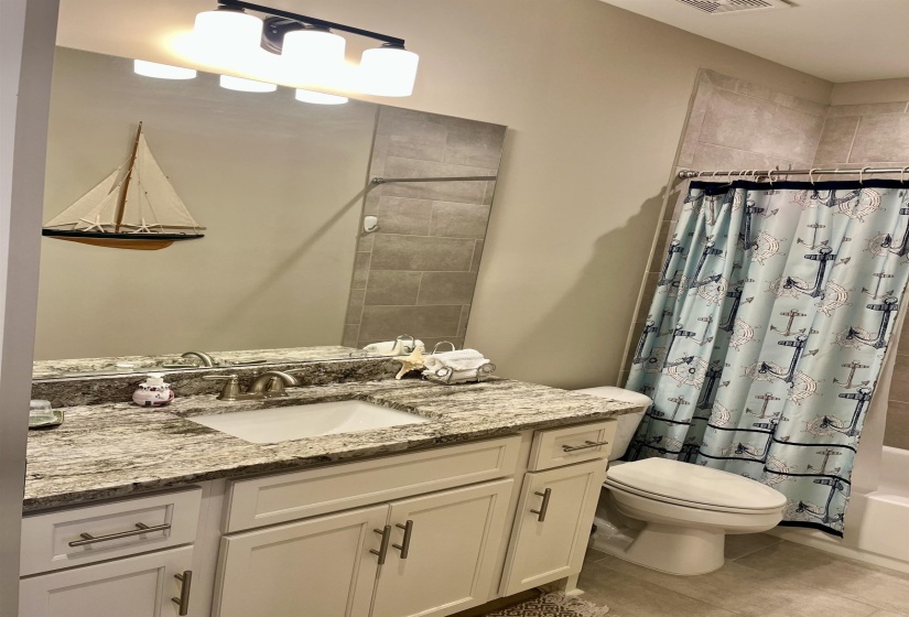 Bathroom featuring vanity, shower / tub combo, and tile patterned floors