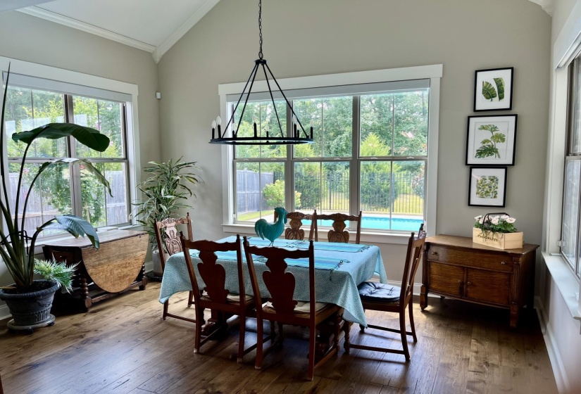Dining area with a chandelier, dark wood-style floors, vaulted ceiling, and ornamental molding
