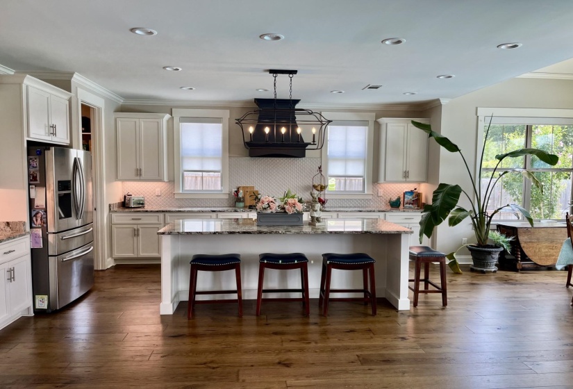 Kitchen featuring crown molding, stainless steel fridge with ice dispenser, light stone counters, white cabinets, and recessed lighting
