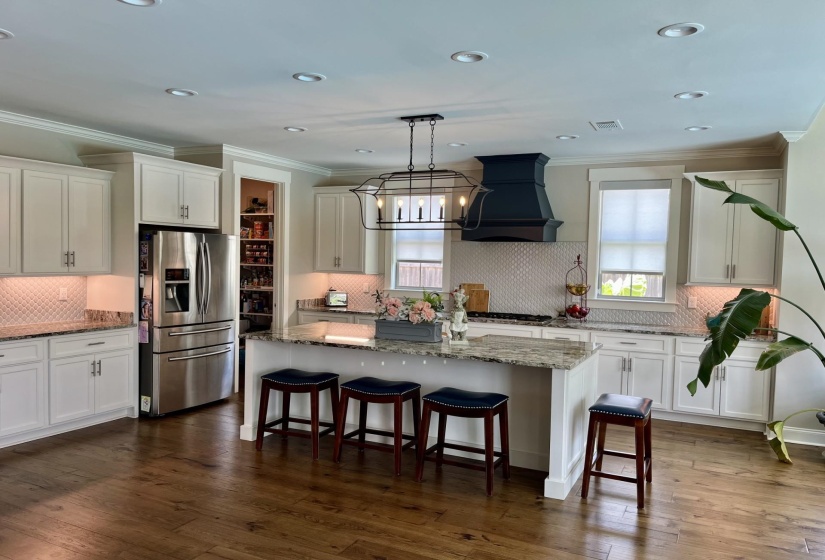 Kitchen featuring ornamental molding, appliances with stainless steel finishes, custom range hood, a center island, and white cabinetry