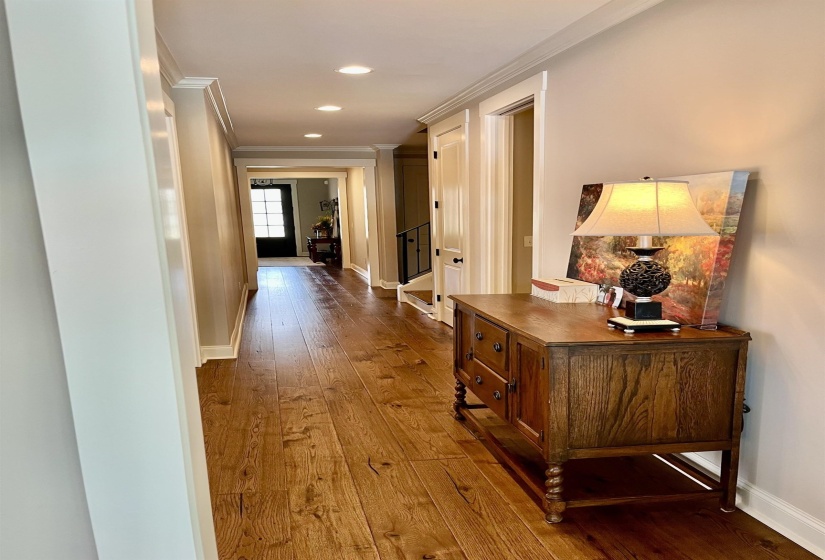 Corridor with dark wood-style flooring, crown molding, stairs, and recessed lighting